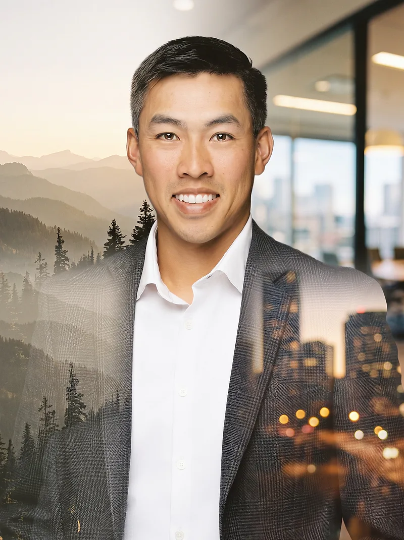 Double-exposure portrait of Phong, smiling, in a blazer: mountains and pine forest through one side, city lights through the other